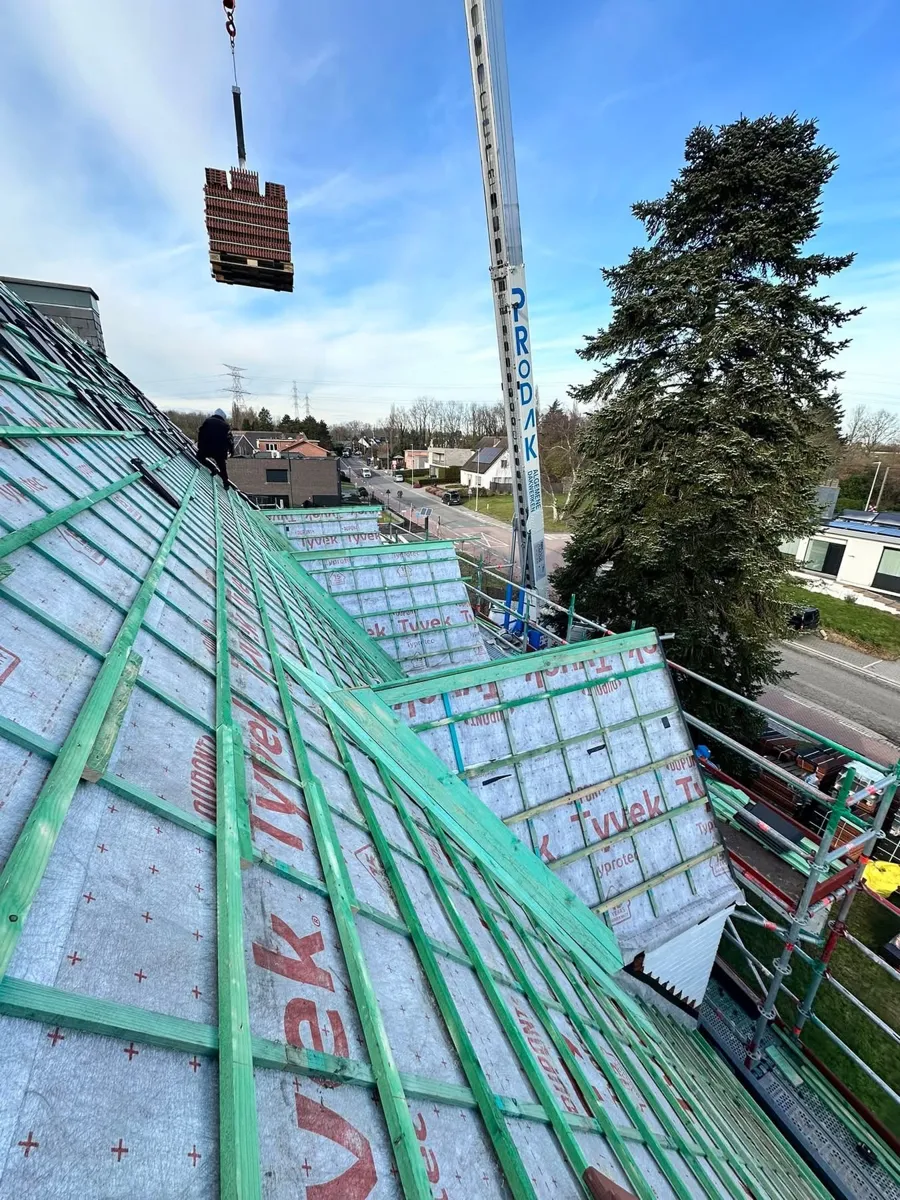 Tijdens: nieuw Tyvek-onderdak en latwerk, dakpannen worden met de Prodak-kraan aangevoerd