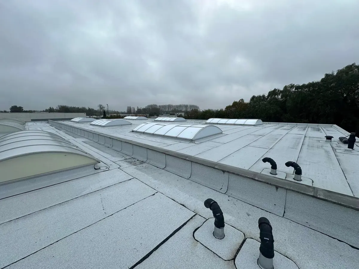 Na: afgewerkt wit roofingdak met lichtstraten en nieuwe doorvoeren