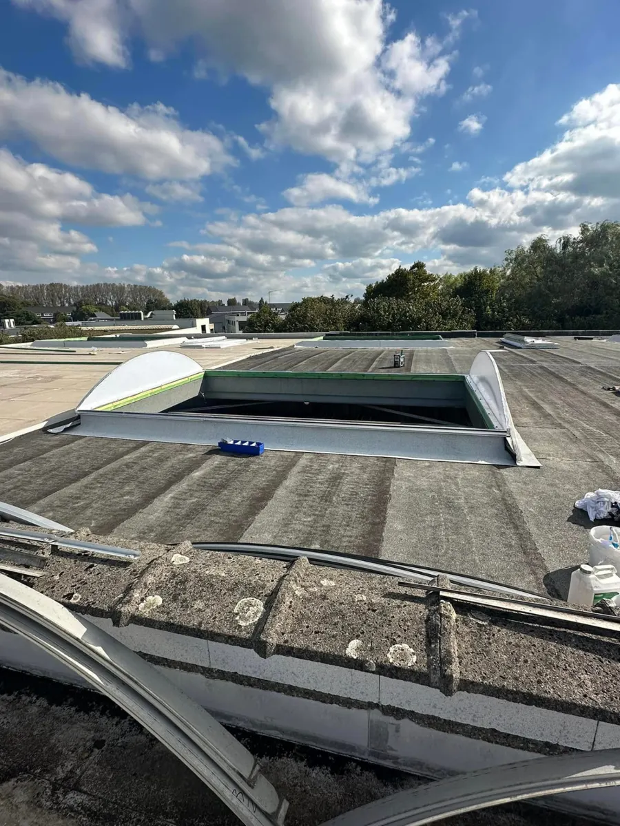 Voor: oud, verweerd bitumen plat dak van het magazijn in Kruibeke met lichtstraatopening