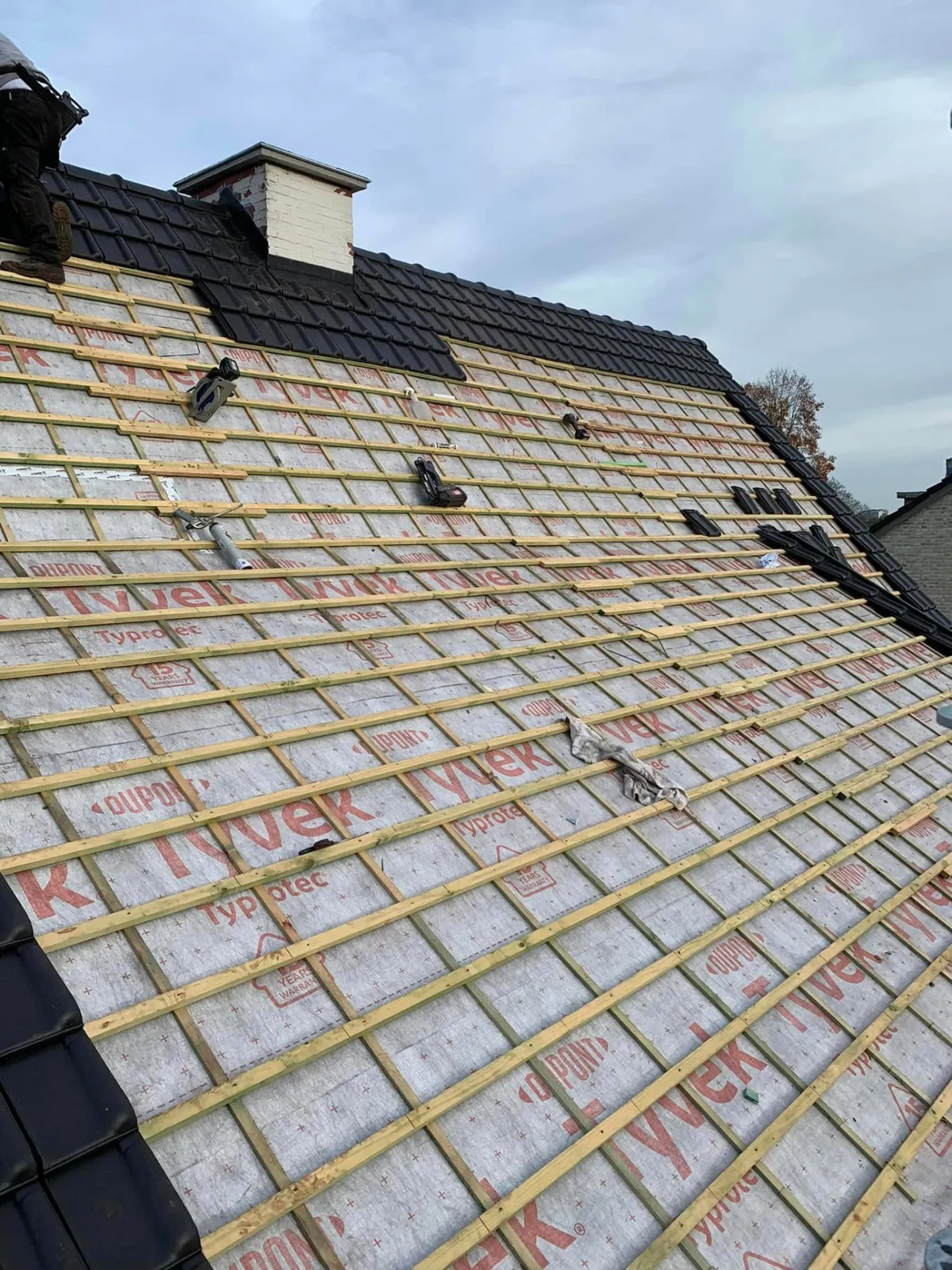 Tijdens: nieuw latwerk op het Tyvek-onderdak, eerste zwarte pannen aan de nok