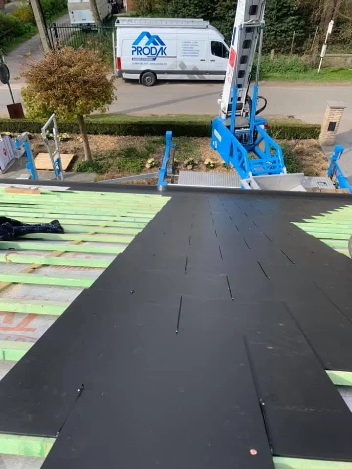 Tijdens: zwarte kunstleien leggen op het nieuwe latwerk, Prodak-bestelwagen op straat