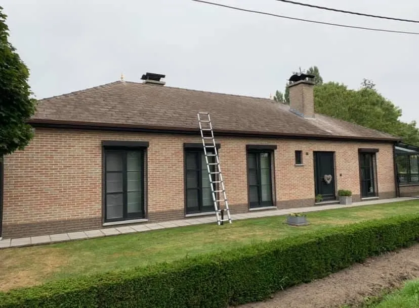 Voor: bungalow met verweerd bruin dak van asbestleien en aluminium goten