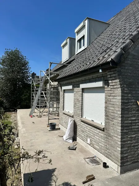 Woning met steiger en nieuw gemonteerde donkere bakgoot – dakwerk door Prodak, Temse