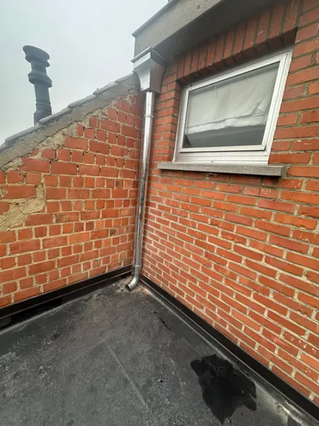 Zinken afvoer met vergaarbak naast een dakvenster op een plat dak – dakwerk door Prodak, Temse