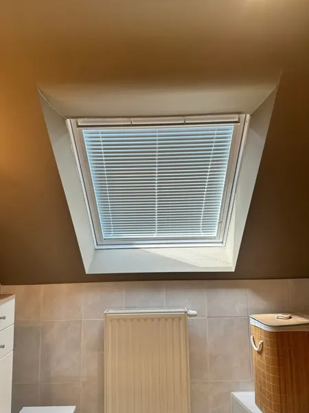 Nieuw Velux-dakraam in een badkamer met binnenzonwering – dakwerk door Prodak, Temse