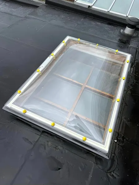 Detail van een rechthoekige lichtkoepel op een zwart plat dak – dakwerk door Prodak, Temse