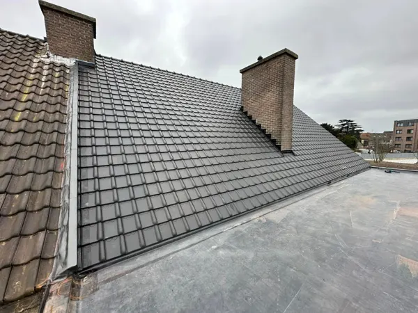 Nieuw antraciet pannendak met aansluitingen rond de schouwen – dakwerk door Prodak, Temse