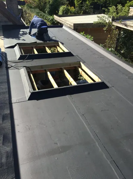 Dakwerker werkt de EPDM-opstanden rond twee koepelopeningen af – dakwerk door Prodak, Temse