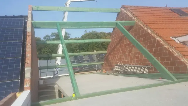 Eerste gedrenkte balken van een nieuwe dakkapel tussen twee gevels, met de Prodak-kraan op de achtergrond – dakwerk door Prodak, Temse